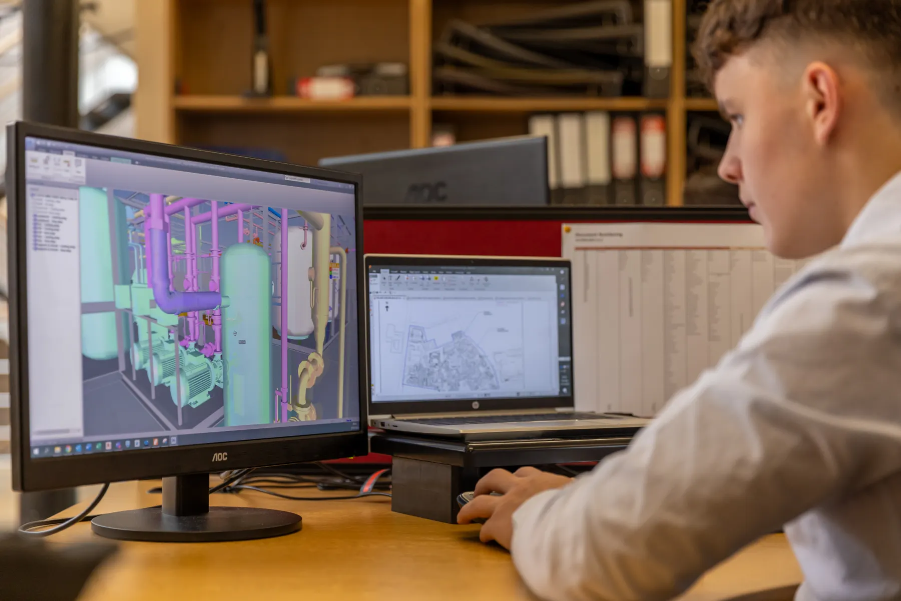 工程师在双屏工作台查看三维 CAD 管路模型与工程图纸